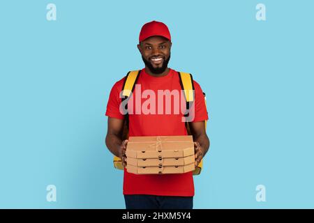 Portrait Of Black Delivery Guy In Uniform Holding Stapel Von Pizzakartons Stockfoto