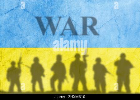 Flagge der Ukraine auf einer Betonwand mit Soldaten Schatten und Inschrift Krieg gemalt. Krise in den internationalen Beziehungen, russische militärische Invasion Stockfoto