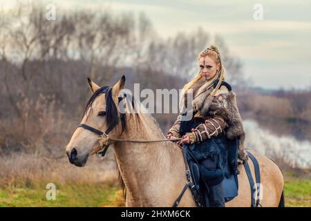 Porträt der schönen wikingerfrau Krieger mit gemaltem Gesicht und Zöpfen Reiten Pferd im Wald Stockfoto