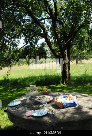 Sommermittagessen auf einem Steintisch im Obstgarten Stockfoto