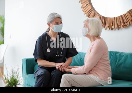 Alte Frau mit Krankenschwester auf Termin zu Hause Stockfoto