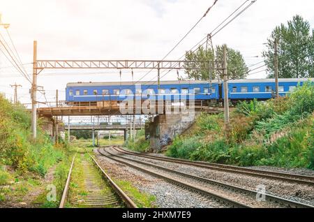 Zug ein Personenwagen fährt entlang einer Eisenbahnbrücke durch eine befreundete Eisenbahn Stockfoto