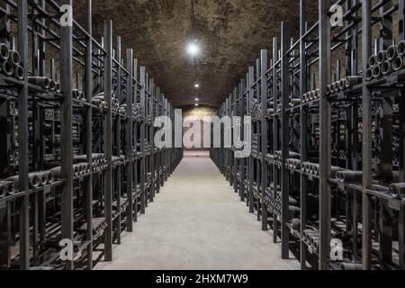 Sehr alte staubige Weinflaschen in einem unterirdischen Keller. Stockfoto