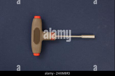 Inbusschlüssel mit braunem Gummigriff auf blauem Hintergrund. Handwerkzeug, Arbeitsgerät zur Reparatur, Schraube festziehen, drehen. Oben, Nahaufnahme. Stockfoto