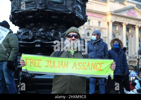 Eine kleine Gruppe von Demonstranten, die Plakate halten, setzt sich dafür ein, Julian Assange aus dem Gefängnis im Piccadilly Circus, London, Großbritannien, zu befreien Stockfoto