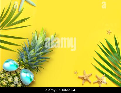 Sommer Hintergrund Design Konzept. Draufsicht auf den Urlaubsstrand mit Seesternen, Ananas und Palmenblättern auf gelbem Hintergrund. Stockfoto