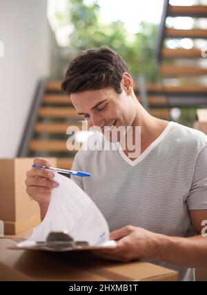 Ich habe alle meine Boxen bekommen - bereit zum Einzug. Ein glücklicher junger Mann, der für die Lieferung verpackter Kartons unterschrieben hat. Stockfoto