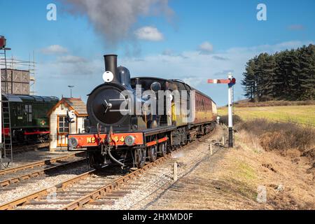 Dampfzug nähert sich an einem blauen Himmel dem Bahnhof der Poppy Line in Weybourne in North Norfolk, Großbritannien Stockfoto