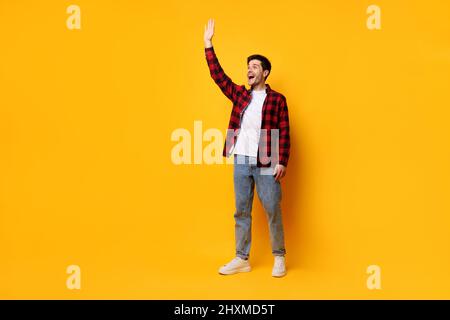 Porträt eines glücklichen jungen Mannes, der in einem gelben Studio posiert Stockfoto