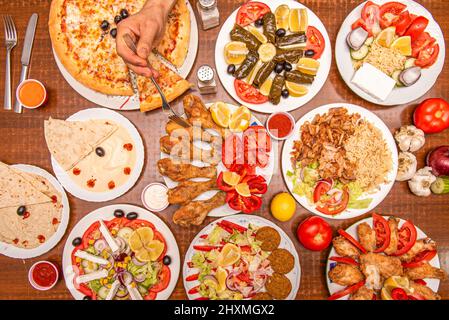 Set von Gerichten mit asiatischen, arabischen und mediterranen Speisen mit gebratenem Huhn, Falafel, Kichererbsen Hummus, Tomatensalat, Rebe-sarma, basmati Reis und ein Mann Stockfoto