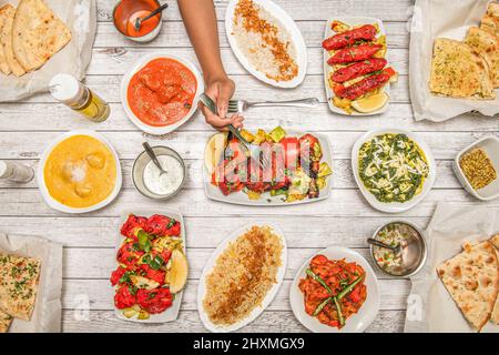 Indische Gerichte, mit gebratenem Huhn Tikka Masala, Knoblauch Naan, Joghurt-Creme, Korma, Tandoori-Huhn, Tomatensalat, Palak Paneer, Pfeffer, Basmati r Stockfoto