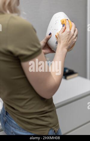 Eine Frau wischt eine eiförmige Vase mit einem Lappen ab. Hochwertige Fotos Stockfoto