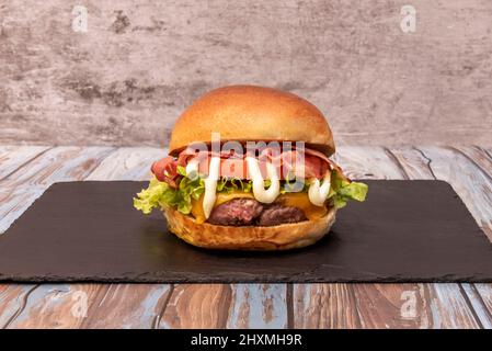 Rindfleisch mit Buchenholz geräuchertem Speck auf einer Basis von Romaine-Salat, Tomaten, spezielle Sauce auf klassischem Brot. Stockfoto