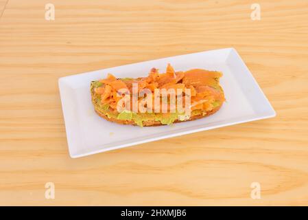 Dank der Neutralität des Brotes gibt es unzählige Rezepte für Toast mit geräuchertem Lachs, obwohl es in diesem Fall mit Guacamole serviert wird Stockfoto