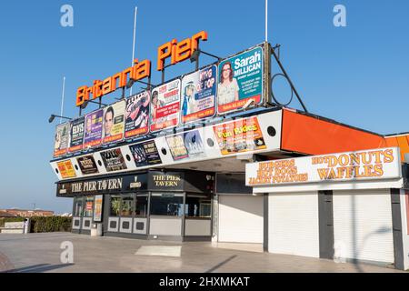 Farbenfroher Eingang zum Britannia Pier mit Plakaten der bevorstehenden Unterhaltung an einem klaren blauen Himmel in Great Yarmouth in Norolk, Großbritannien Stockfoto