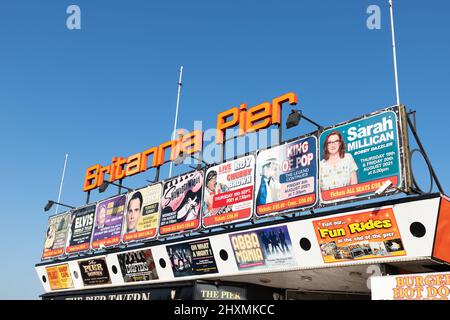 Farbenfroher Eingang zum Britannia Pier mit Plakaten der bevorstehenden Unterhaltung an einem klaren blauen Himmel in Great Yarmouth in Norfolk, Großbritannien Stockfoto