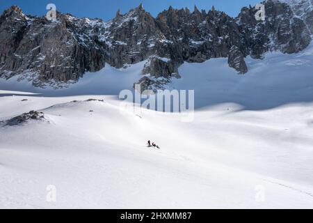 Drei Skitourengeher machen eine Pause auf dem Gletscher unterhalb des Periades-Gebirges an der Grenze zwischen Italien und Frankreich oberhalb des Vallee Blanche in C Stockfoto