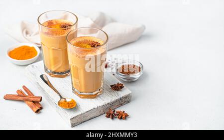 Cappuccino mit Kurkuma, Zimt und Anise in zwei Gläsern auf weißem Grund. Seitenansicht, Kopierbereich. Stockfoto
