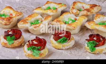 Frisches, hausgemachtes Gebäck. Mischung aus Blätterteig und Vorspeisen. Rosafarbter Pfefferoni-Kuchen. Gebäck mit Salami. Stockfoto