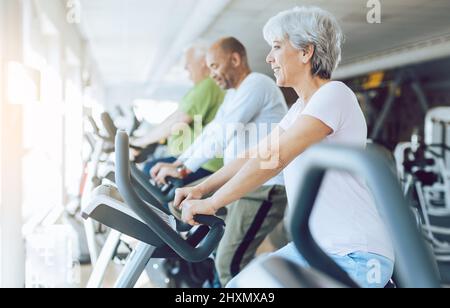 Fit Senioren auf stationären Fitness-Bikes im Fitnessstudio Stockfoto