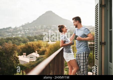 So verbringen wir unsere Wochenenden. Aufnahme eines liebevollen jungen Paares, das morgens auf dem Balkon zu Hause Kaffee trinkt. Stockfoto