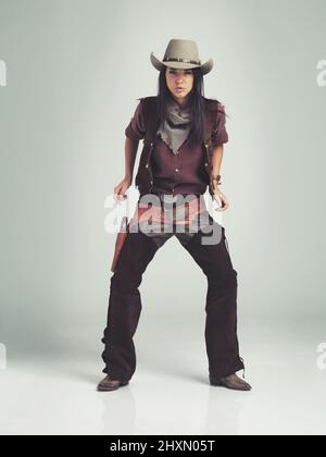 Ich bin der Sheriff um diese Teile.... Ganzkörperaufnahme einer attraktiven jungen Frau in Cowboy-Kleidung. Stockfoto