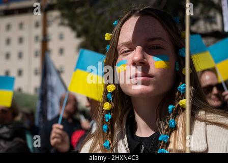 Madrid, Spanien. 13. März 2022. Eine Protesterin sah während einer Kundgebung gegen die russische Invasion in der Ukraine blaue und gelbe Haarbänder und eine ukrainische Flagge auf ihrem Gesicht tragen. Tausende von pro-ukrainischen Demonstranten demonstrieren gegen die russische Invasion, während sie sich von der Plaza de Espana (Spanischer Platz) zum Puerta del Sol-Platz in Madrid, Spanien, versammeln. Kredit: SOPA Images Limited/Alamy Live Nachrichten Stockfoto