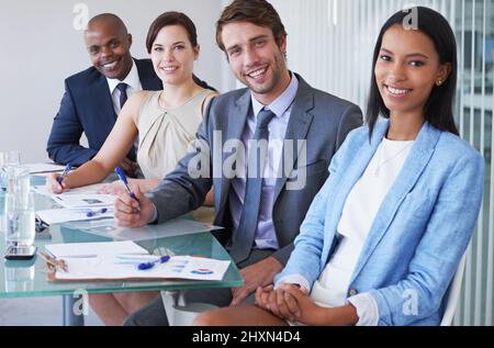 Sie haben sich in der Finanzwelt ausgezeichnet. Porträt einer Gruppe von Geschäftsleuten, die an einem Konferenztisch sitzen. Stockfoto
