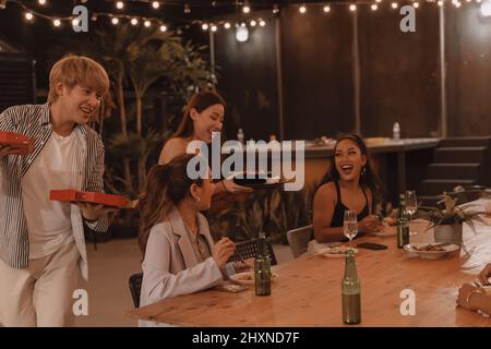 Junge asiatische Freunde essen und genießen gemeinsam das Abendessen im Restaurant im Freien. Freundschaft und Wiedersehensfeier Stockfoto