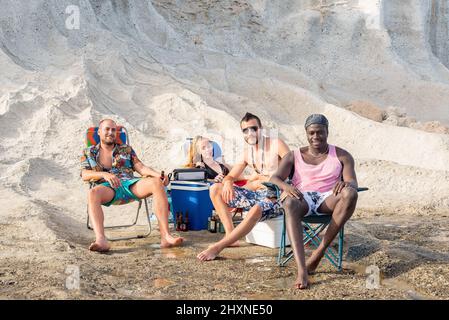 Vier Freunde sitzen am Strand und machen ein Picknick Stockfoto
