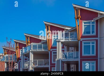 Brandneues Apartmentgebäude an sonnigen Tagen in BC, Kanada. Moderne kanadische Wohnarchitektur. Niemand, Straßenbild, vertikal Stockfoto