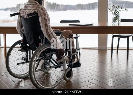 Junger, zeitgenössischer afroamerikanischer Geschäftsmann mit Lähmung, der sich mit einem Laptop auf den Tisch bewegt, während er zur Arbeit geht Stockfoto