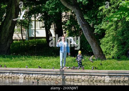 Mutter und Tochter füttern auf dem Stadtteich Semmelbrösel an Tauben Stockfoto