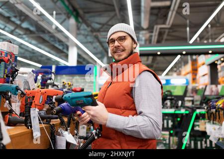 Kunde in einem Hardwareladen neben einem Showcase mit Elektrowerkzeugen Stockfoto