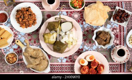 Ketupat Lebaran. Traditionelles festliches Gericht aus Reiskuchen oder Ketupat mit verschiedenen Beilagen, beliebt während der Eid-Feierlichkeiten. Stockfoto