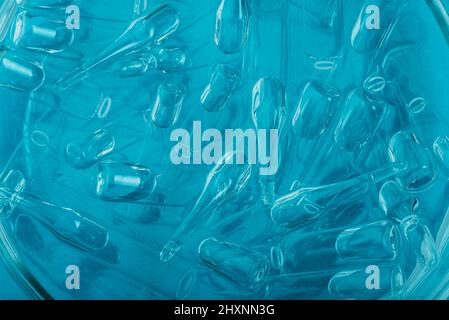 Medizinische Ampullen aus Glas zur Injektion. Medizin ist flüssiges Natriumchlorid mit wässriger Lösung in Ampulla. Nahaufnahme. Flaschen Ampulle Multicolor auf Hintergrundfarbe und Wasser. Humanplasma. Stockfoto