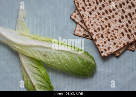 Nahaufnahme von Matzah- und Salatblättern auf hellblauem Hintergrund Stockfoto