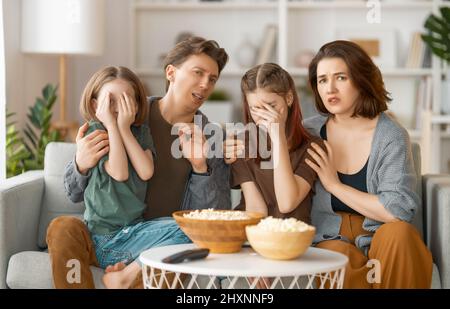 Familie, die zu Hause Projektor, TV, Filme mit Popcorn am Abend sieht. Mutter, Vater und Töchter verbringen Zeit miteinander. Stockfoto