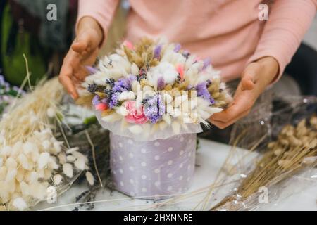 Buntes Bouquet von verschiedenen getrockneten Blumen Totholz Blumen in den Händen einer Floristin Frau. Rustikale Blume Hintergrund. Basteln Sie Blumenstrauß. Der Prozess der Herstellung eines Straußes. Stockfoto