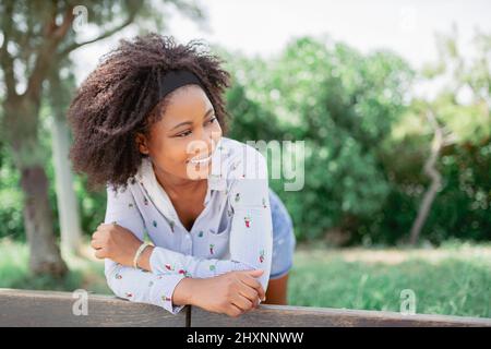 Fröhliche afroamerikanische Frau lächelt, während sie einen Tag im Park genießt. Stockfoto