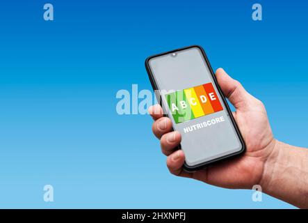 Hand hält ein Smartphone mit einem Nutriscore-Label auf dem Bildschirm Stockfoto