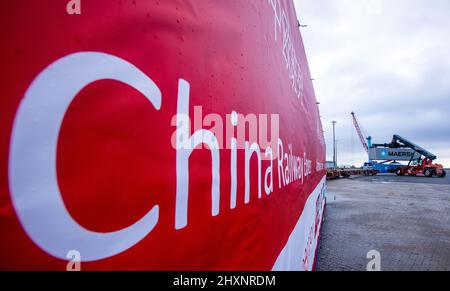 Mukran, Deutschland. 11.. Februar 2022. Ein Banner mit der Aufschrift „China Railway Express“ hängt von einer Lokomotive, die die ersten Container einer neuen „Seidenstraße“-Verbindung zwischen China und Deutschland durch den Seehafen Mukran transportiert. Die Container aus dem chinesischen Wuhan decken einen Teil der Strecke auf dem Wasser ab und werden auf der Insel Rügen wieder auf Schienenfahrzeuge verladen. Quelle: Jens Büttner/dpa-Zentralbild/dpa/Alamy Live News Stockfoto