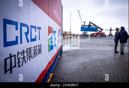 Mukran, Deutschland. 11.. Februar 2022. Ein Banner mit der Aufschrift „China Railway Express“ hängt von einer Lokomotive, die die ersten Container einer neuen „Seidenstraße“-Verbindung zwischen China und Deutschland durch den Seehafen Mukran transportiert. Die Container aus dem chinesischen Wuhan decken einen Teil der Strecke auf dem Wasser ab und werden auf der Insel Rügen wieder auf Schienenfahrzeuge verladen. Quelle: Jens Büttner/dpa-Zentralbild/dpa/Alamy Live News Stockfoto