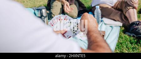 Nicht erkennbare Erwachsene Familie spielt während eines Ausflugs Karten Stockfoto
