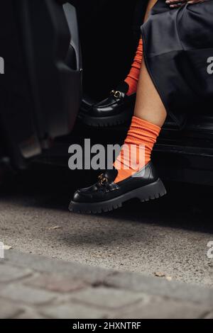 Unverkennbar stilvolle Frau in modischen Schuhen und orange Socken Auskommen aus dem Auto Stockfoto