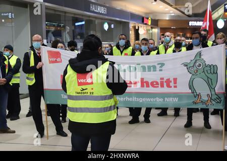 Köln, Deutschland. 14. März 2022. Streikende Fluggastkontrollmitarbeiter haben sich in einem Terminal versammelt. Die Gewerkschaft Verdi hat das Sicherheitspersonal bei der Passagierkontrolle an mehreren deutschen Flughäfen aufgefordert, am Montag ganztägige Warnstreiks zu starten. Sie sind Teil des Lohnstreits zwischen Verdi und dem Bundesverband der Luftfahrtunternehmen (BDLS). Die Gewerkschaft verhandelt derzeit über einen neuen Tarifvertrag mit dem Arbeitgeberverband für rund 25.000 Sicherheitspersonal im ganzen Land. Quelle: Sascha Thelen/dpa/Alamy Live News Stockfoto