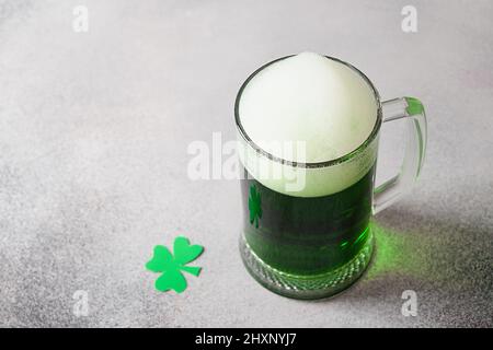 Patrick's Day grünes Bier in Pint auf grauem Hintergrund. Nahaufnahme. Shamrock Symbol des Glücks. Speicherplatz kopieren. Stockfoto