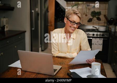 kaukasische ältere Frau liest glücklich Versicherungsdokument mit Brille Stockfoto