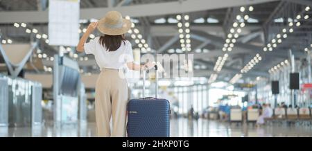 Junge Frau Hand halten Gepäck Griff vor der Überprüfung der Flugzeit in Flughafen, Transport, Versicherung, Reise-und Urlaubskonzepte Stockfoto