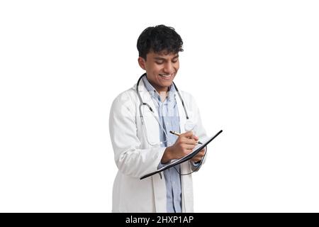 Junger peruanischer Arzt lächelt und schreibt isoliert einen medizinischen Bericht. Stockfoto